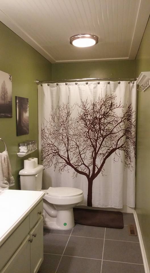 a bathroom with a tree shower curtain and toilet