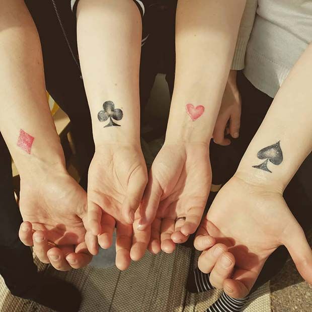 three people holding hands with tattoos on their arms and two playing cards tattooed on their wrists