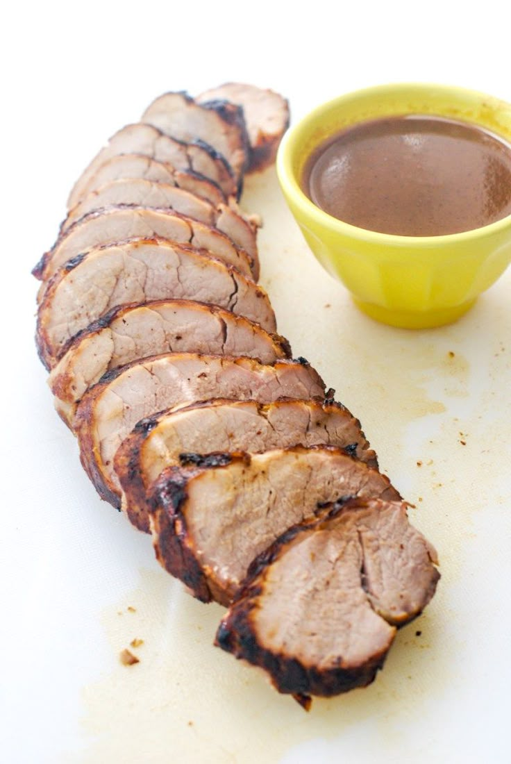 sliced meat and dipping sauce on a cutting board