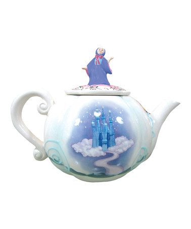 a teapot with a castle painted on the side and a person standing on top