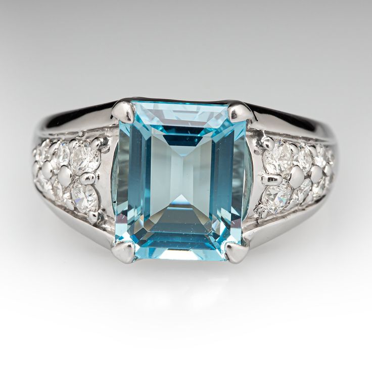 This cool-hued ring is centered with one (1) emerald cut natural aquamarine set into a four-prong setting. The shoulders of the ring are each accented with eight (8) shared bead set round brilliant cut diamonds. The ring measures 10.7mm at the top, rises 6.7mm above the finger, and tapers to 2.9mm wide by 1.0mm thick at the base of the shank. The ring is crafted in platinum and is currently a size 6.25. Elegant Emerald Cut Platinum Gemstone, Elegant Octagon Topaz Ring With Center Stone, Elegant Emerald Cut Gemstones With Accent Stones, Elegant Emerald Cut Blue Gemstones, Modern Octagon Topaz Gemstone Ring, Elegant Blue Emerald Cut Gemstones, Modern Octagon Topaz Ring, Elegant Octagon Topaz Promise Ring, Elegant Octagonal Topaz Ring