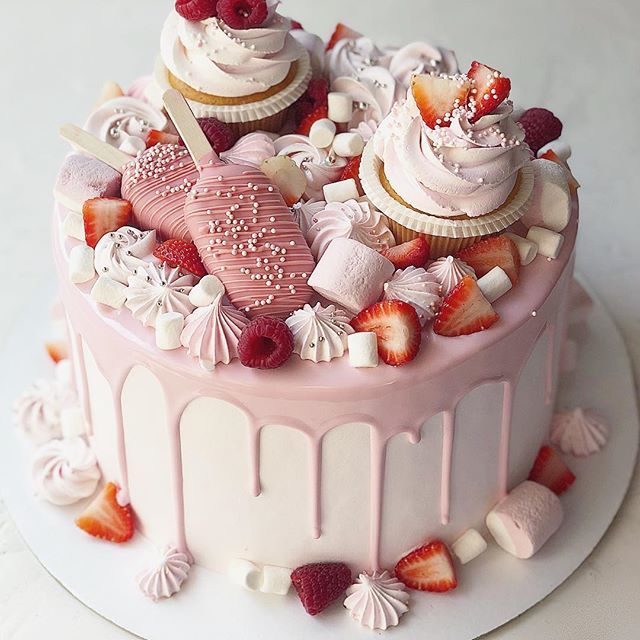 there is a pink cake with white frosting and strawberries on the top it