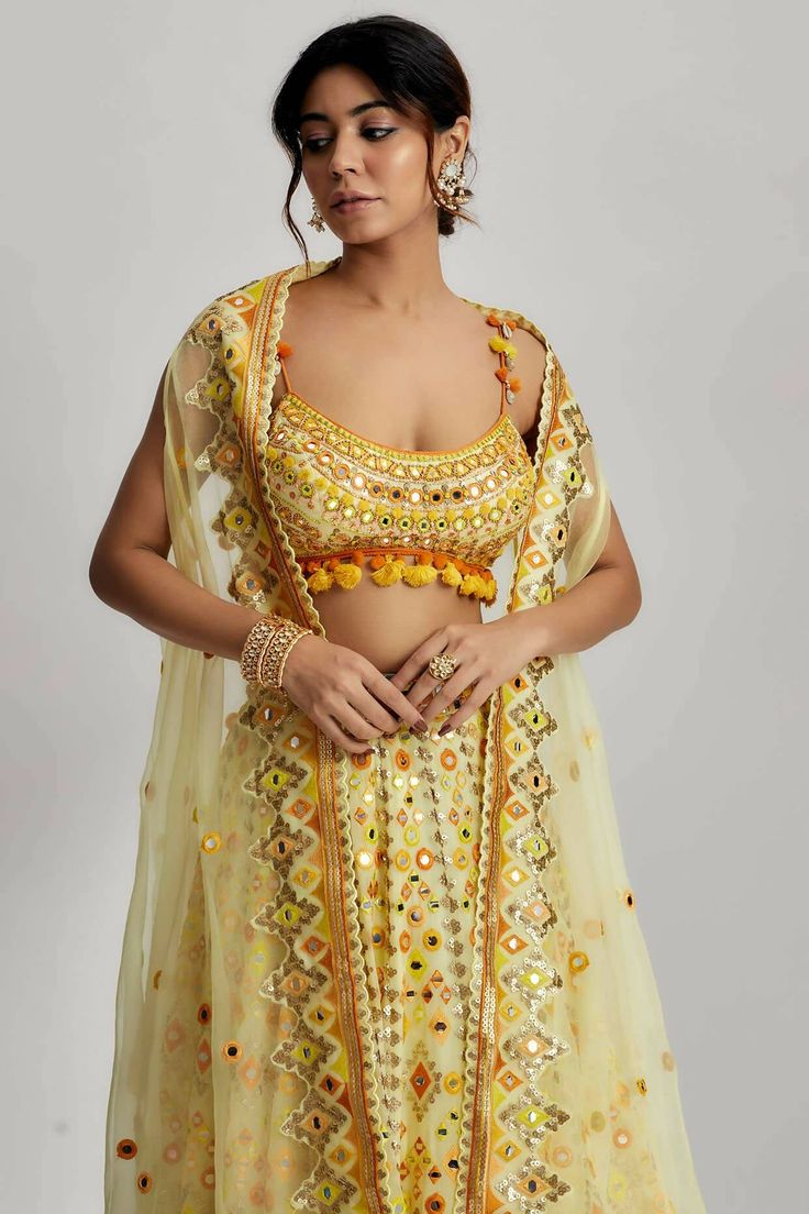 To further enhance its beauty, the ashi lehenga is adorned with pompoms and tassels. These playful elements add a whimsical touch and create a sense of movement as you glide across the dance floor. The pompoms and tassels are meticulously crafted and delicately attached, ensuring they stay in place throughout your glamorous wedding ceremony. Diwali Party Sets With Latkans, Party Sets With Latkans For Diwali, Bohemian Gota Work Dresses For Diwali, Bohemian Dress With Gota Work For Diwali, Bohemian Anarkali Set With Dori Work, Bohemian Sharara With Gota Work For Reception, Bohemian Sets With Tassels For Navratri, Festive Sharara With Tassels And Traditional Drape, Festive Traditional Drape Sharara With Tassels