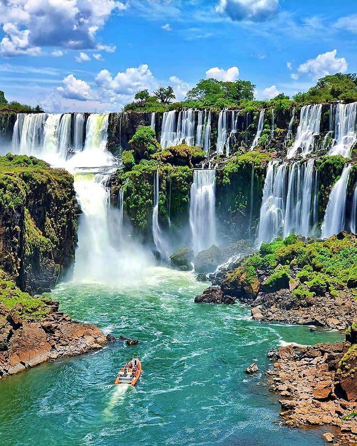 a person in a kayak on the side of a large body of water surrounded by waterfalls