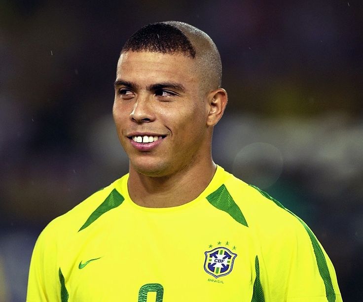 a soccer player is smiling and wearing a yellow shirt with green trim on his face