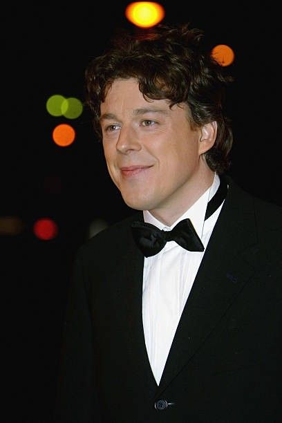 a man in a tuxedo smiles at the camera