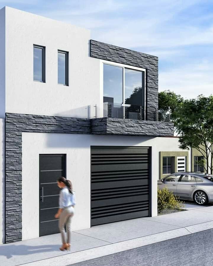 a woman walking down the sidewalk in front of a white and gray house with black garage doors