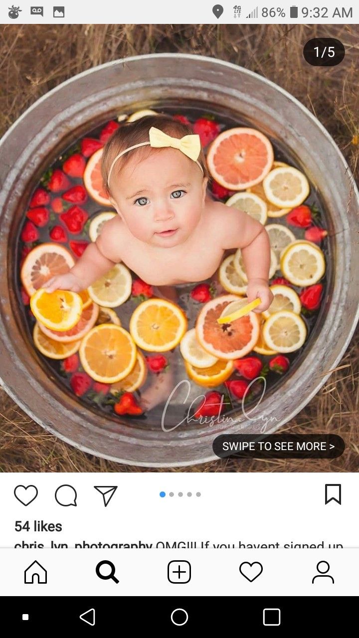 a baby sitting in a tub filled with oranges and strawberries on top of it