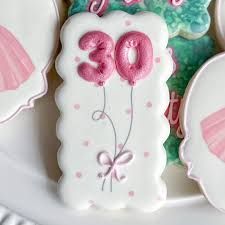 decorated cookies on a plate with the number twenty one in pink and white icing