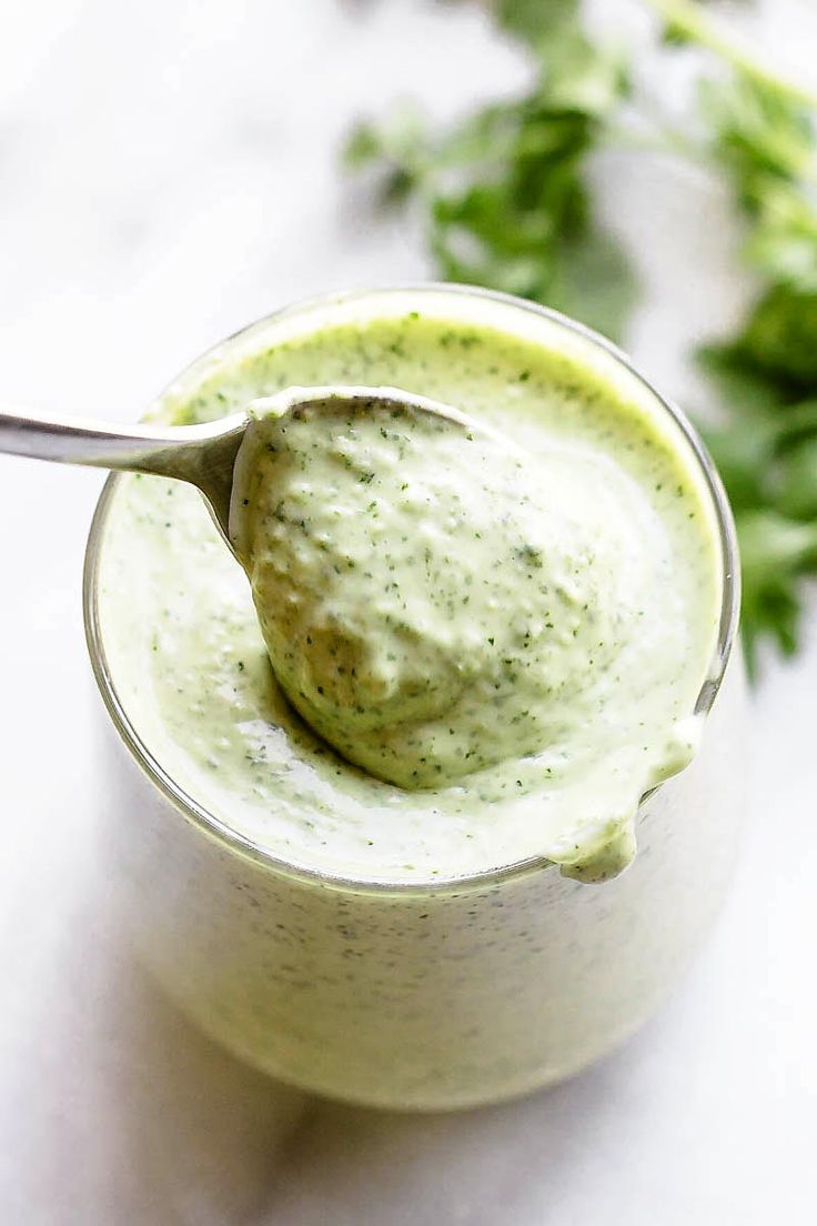 a spoon in a small glass filled with green sauce