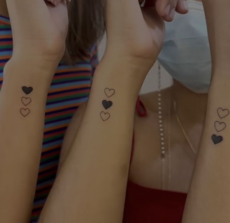 three girls with matching tattoos on their arms