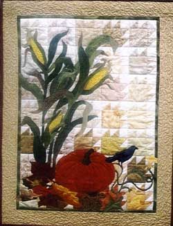 a quilted wall hanging with flowers and a bird on it's back side