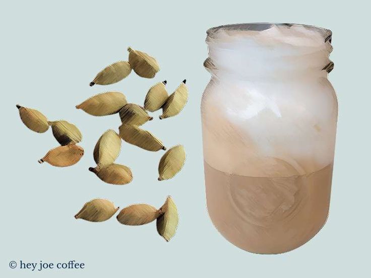 a jar filled with almonds next to a pile of nuts on a blue background