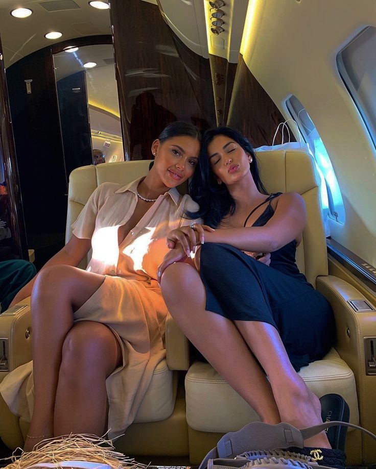 two beautiful women sitting on top of an airplane