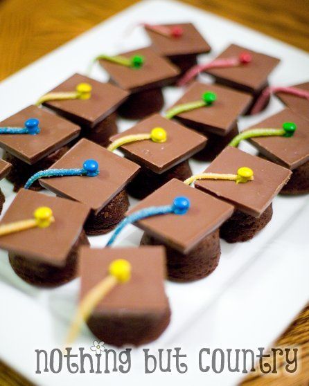 chocolate graduation cookies are arranged on a white plate with colorful pins and tassels