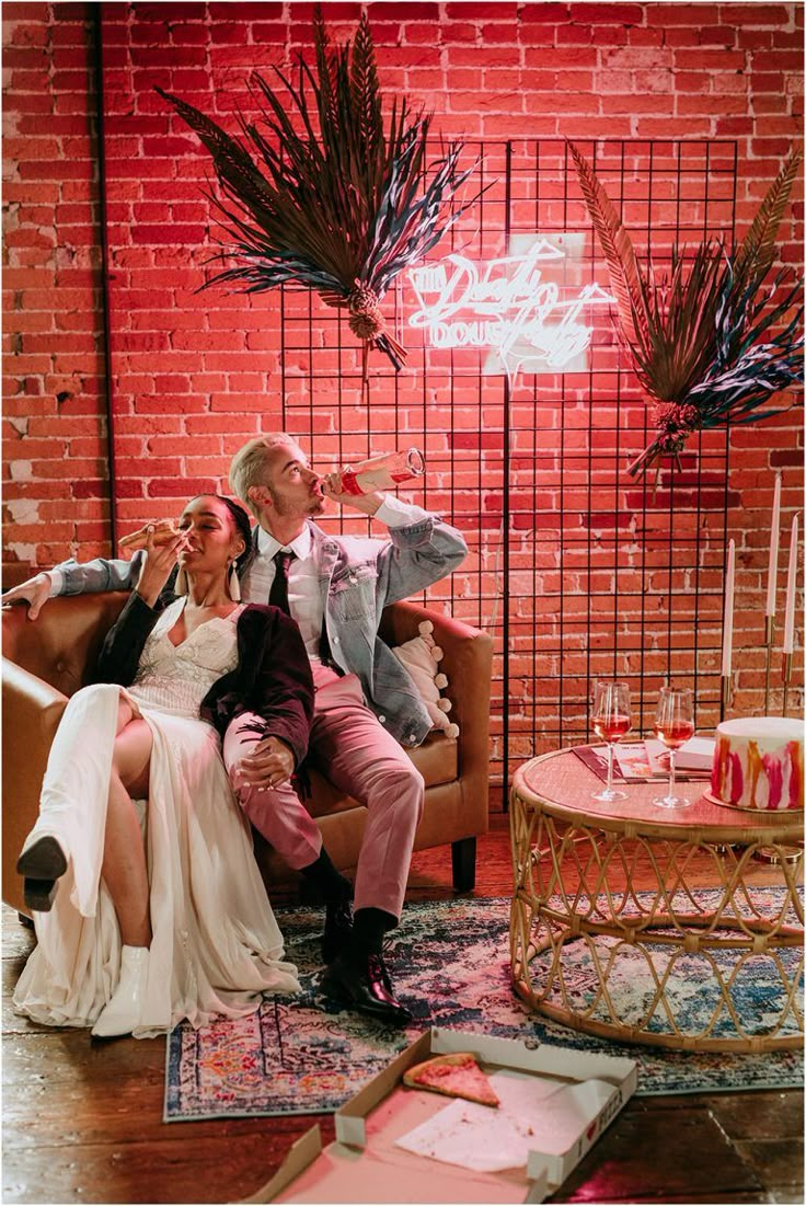 a man and woman sitting on a couch in front of a brick wall