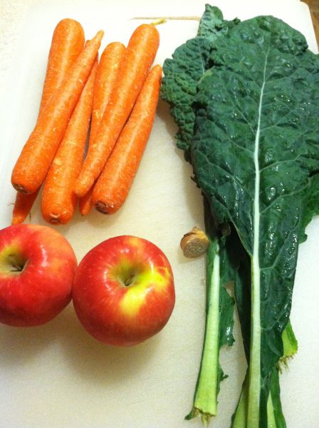 carrots, apples, and spinach on a cutting board with some type of vegetable