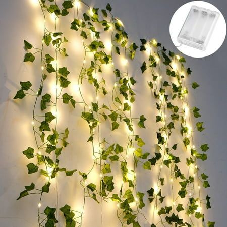 ivy vines are growing on the side of a wall with fairy lights strung from it