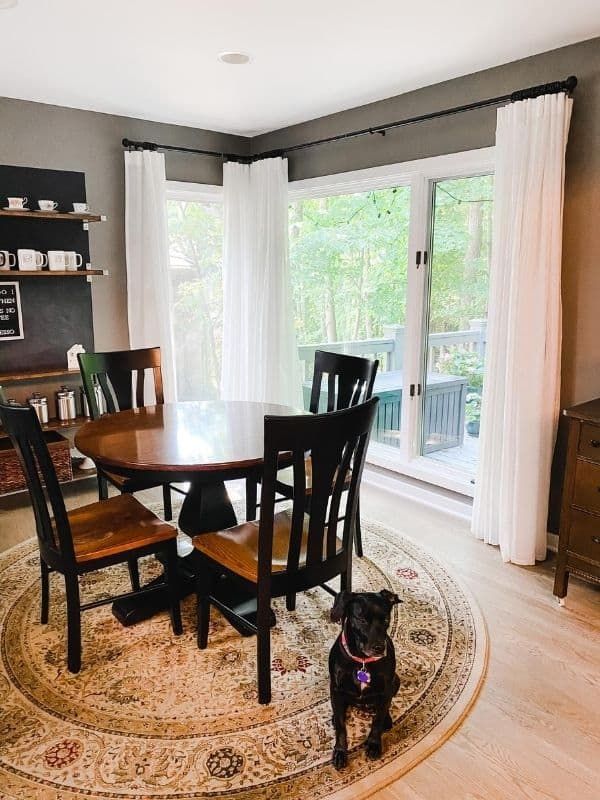 a dining room table and chairs with a dog sitting on the rug in front of it