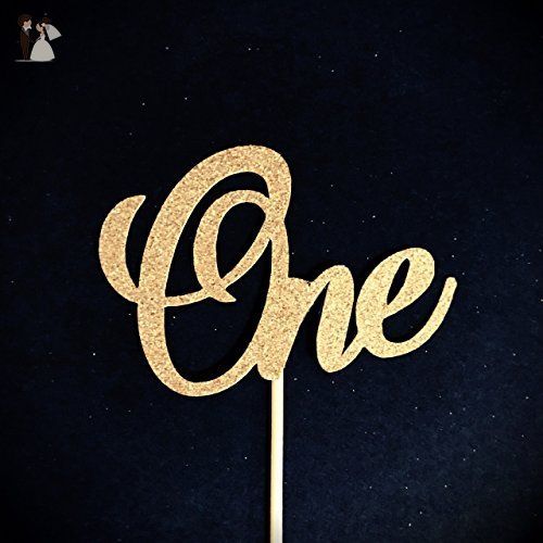 a cake topper with the word one on it in gold sparkles against a black background