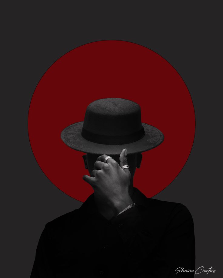 a man wearing a hat and holding his hand up to his face in front of a red circle