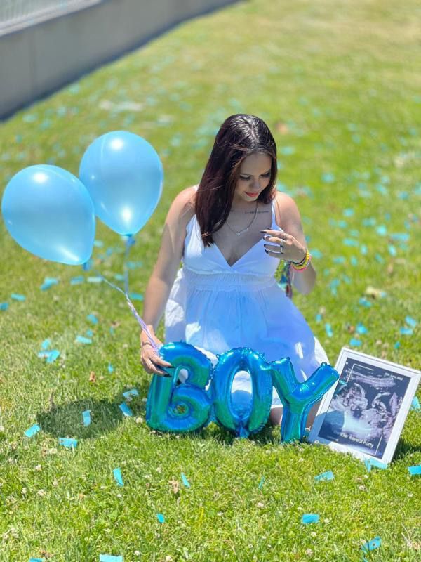 a woman sitting in the grass with balloons