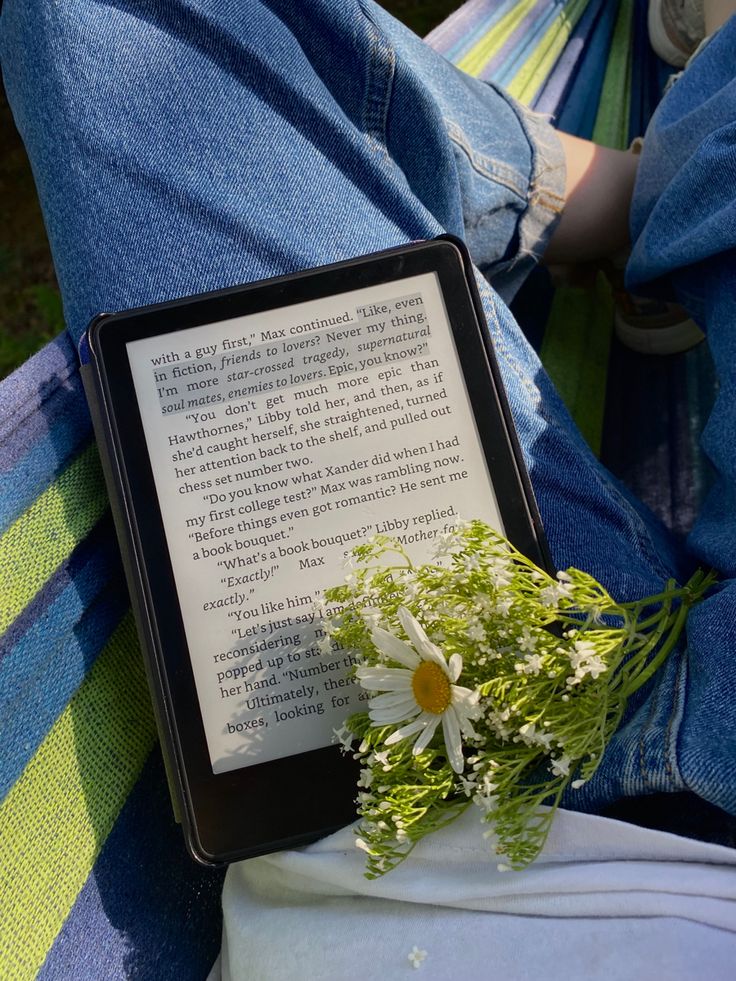 a person sitting in a hammock with a book and flowers on their lap