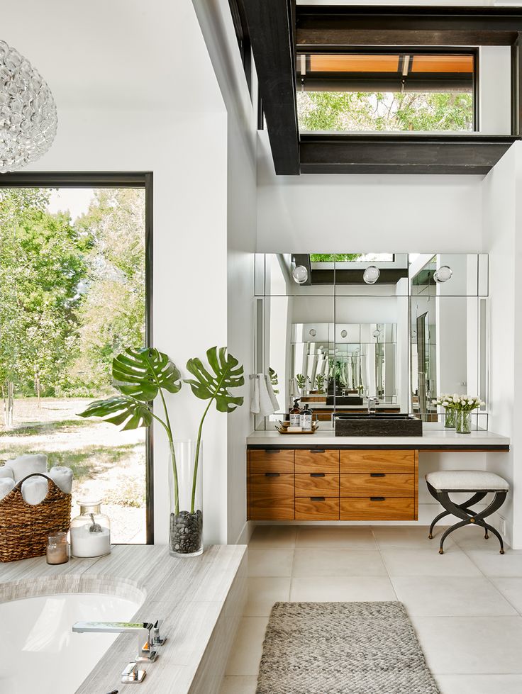 a bathroom with a tub, sink and large windows