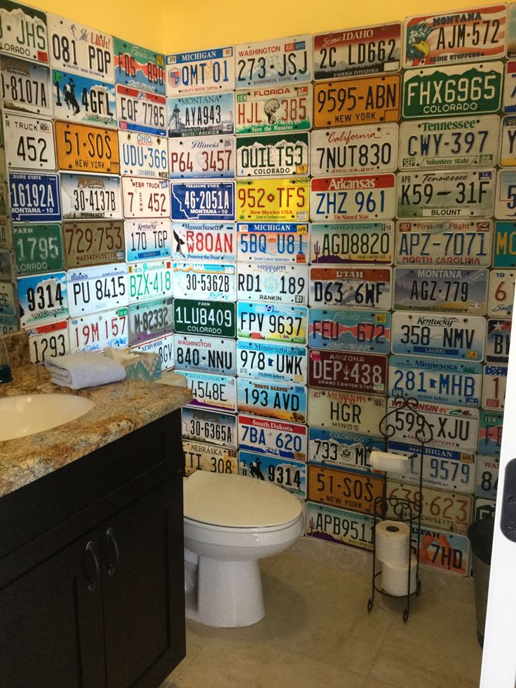 a bathroom with lots of license plates on the wall next to a toilet and sink