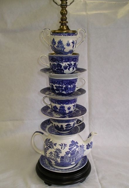 a stack of blue and white teacups with a gold top on a stand