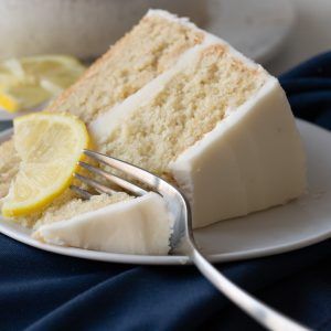 a slice of cake on a white plate with a fork and lemon wedges next to it