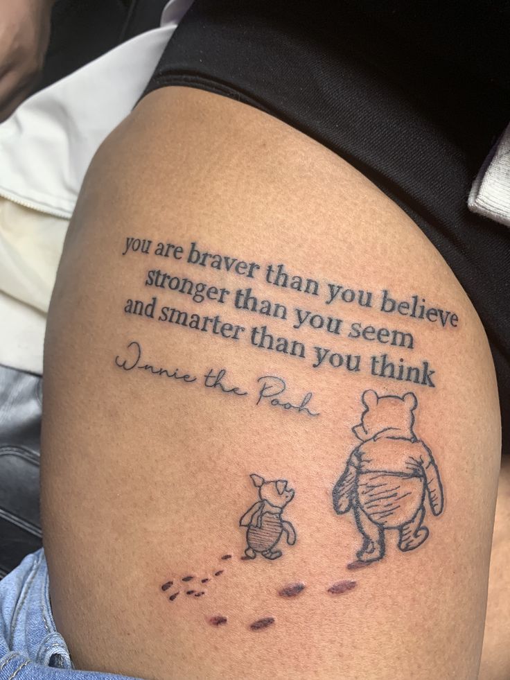 a winnie the pooh tattoo on someone's right thigh that says, you are brave than you believe and smarter than you seem