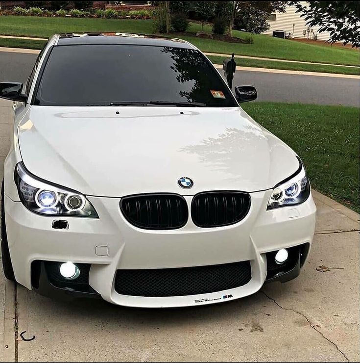 a white car parked on the side of a road next to a tree and grass