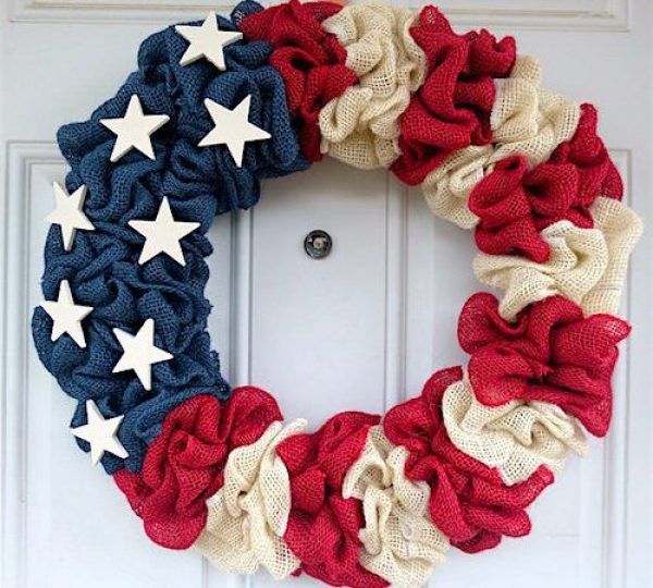 an american flag wreath is hanging on the front door with red, white and blue ruffles