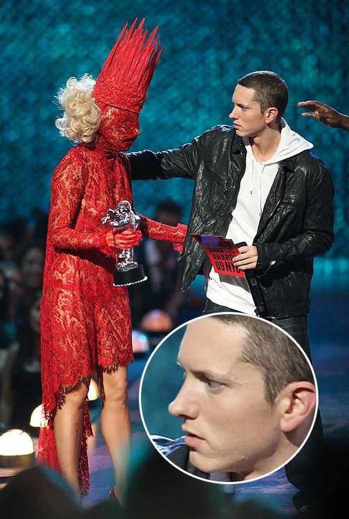 lady in red dress being presented at awards ceremony by man with bird on his head