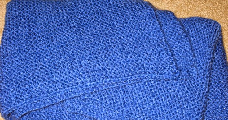 a blue knitted blanket laying on the floor