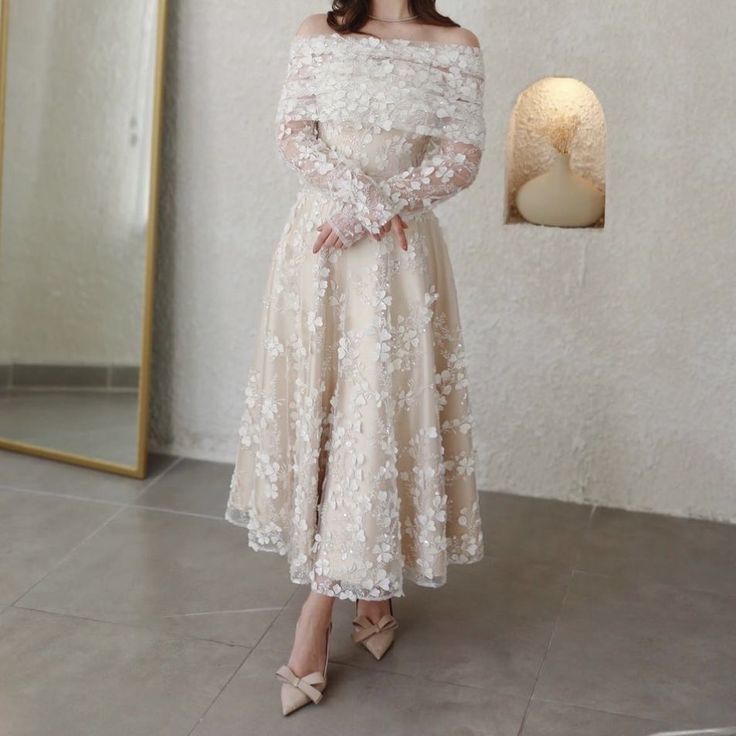 a woman standing in front of a mirror wearing a dress with white flowers on it