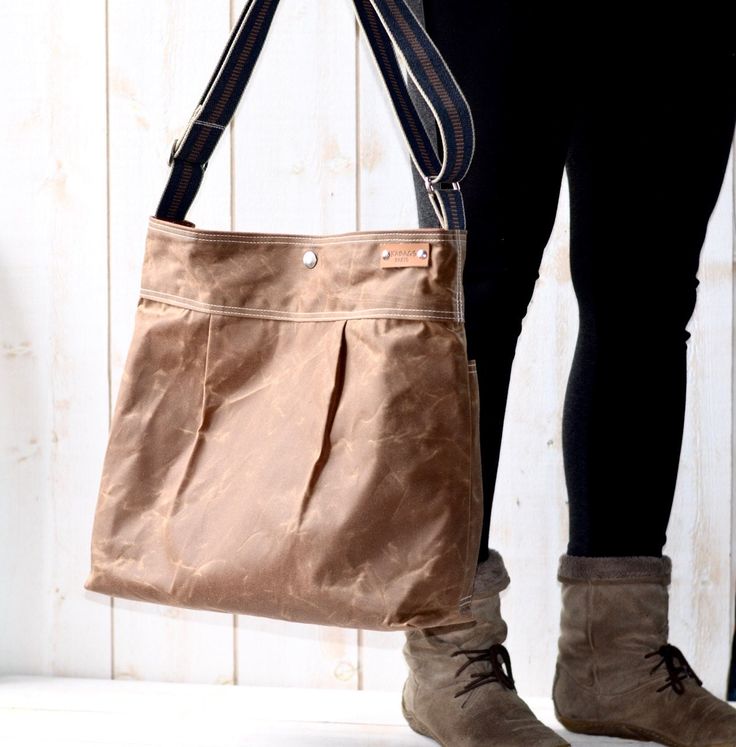 a person holding a brown bag in front of a white wooden wall and wearing black leggings