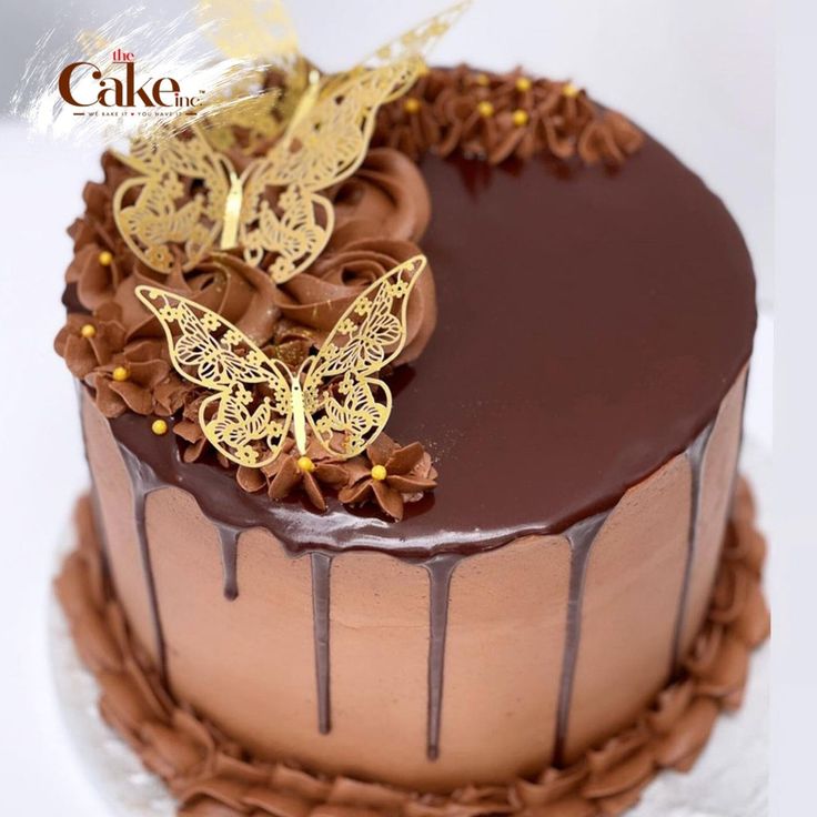 a cake with chocolate frosting and gold butterflies on top, sitting on a plate