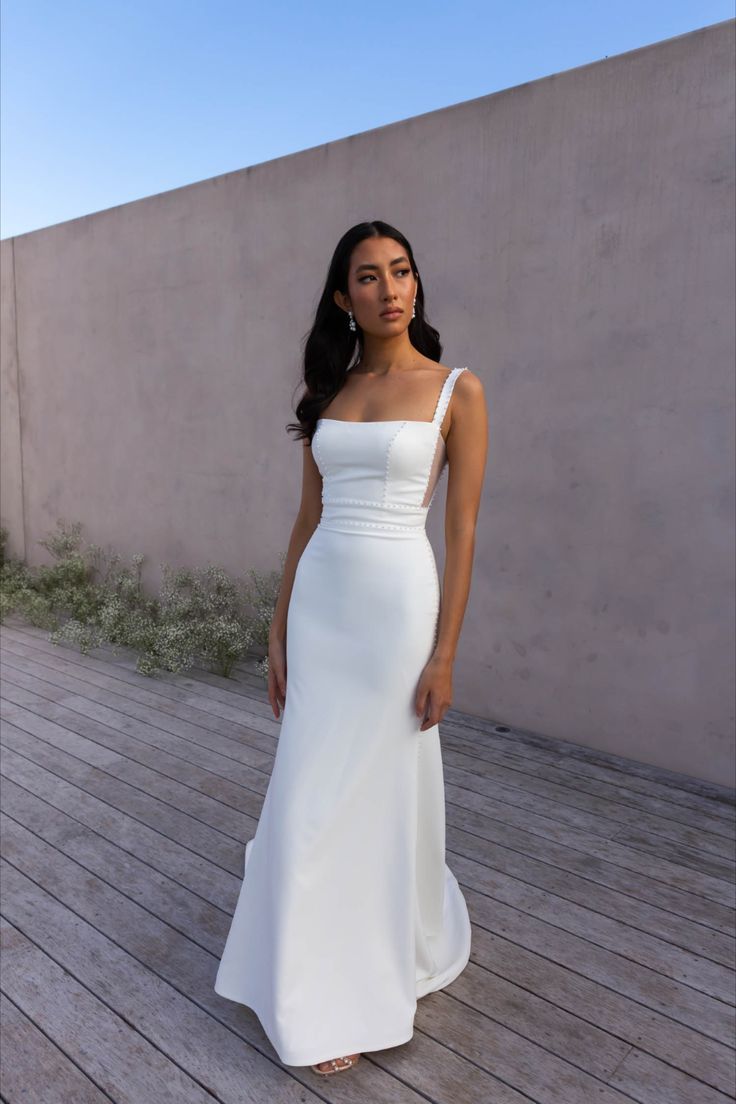 a woman in a white dress standing on a wooden floor