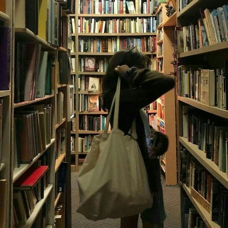 a woman carrying a bag through a library filled with books