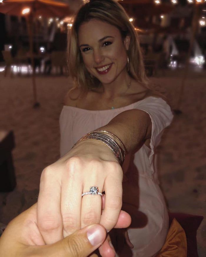 a woman holding the hand of another person with a diamond ring on her finger at night