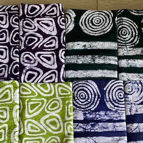 four different colored towels with designs on them sitting next to each other in front of a wooden table