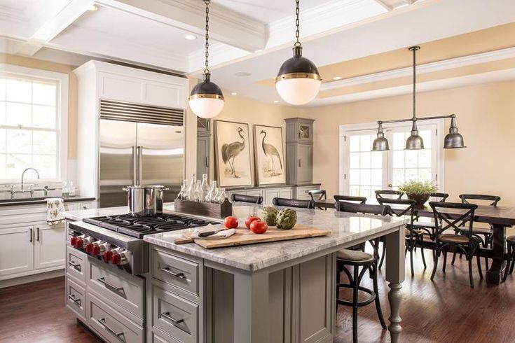 a large kitchen with an island in the middle and two pendant lights hanging from the ceiling