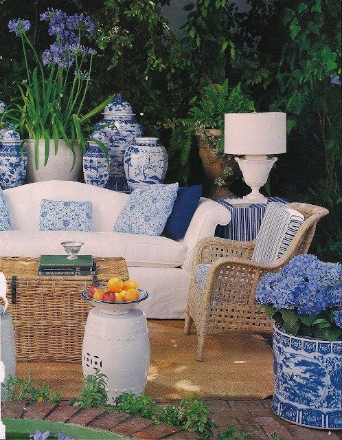 an outdoor living room with wicker furniture and blue and white vases on the table