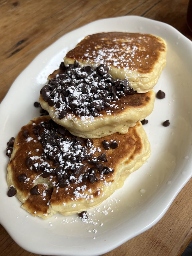 two pancakes on a white plate topped with chocolate chips