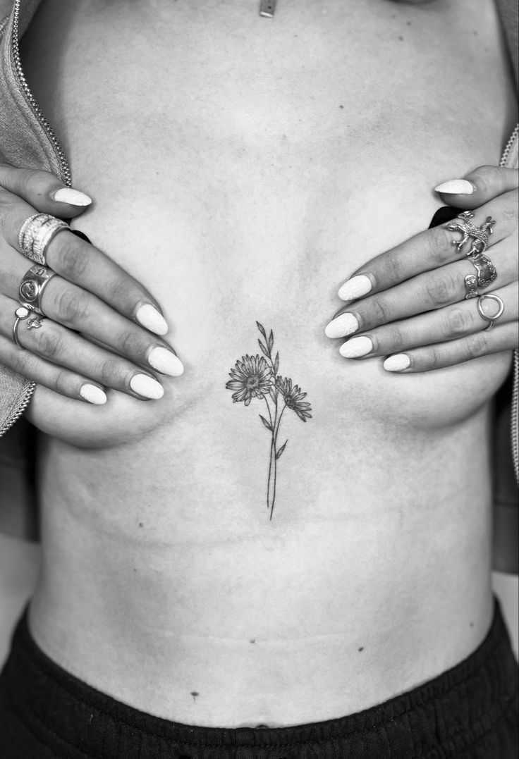 a woman's chest with tattoos and flowers on her left side ribcage