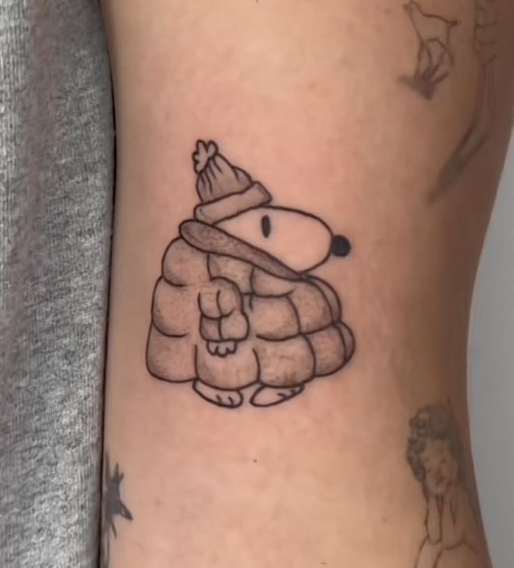 a person with a tattoo on their leg that has a dog wearing a hat and scarf