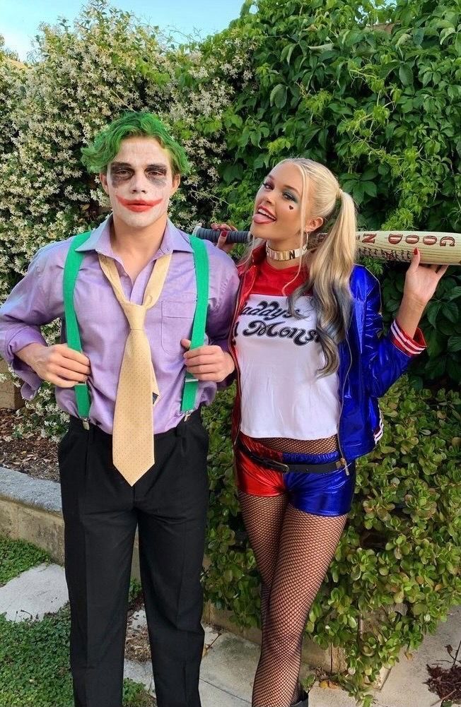 two people dressed up as the joker and harley in front of some bushes, one holding a bat