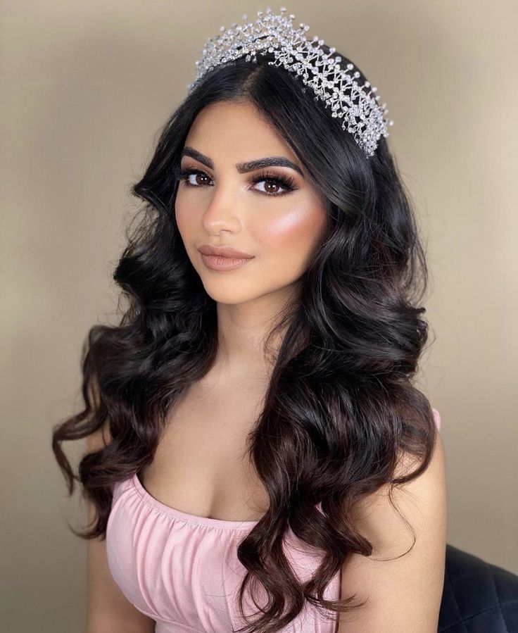 a woman wearing a tiara with long dark hair and brown eyes is posing for the camera